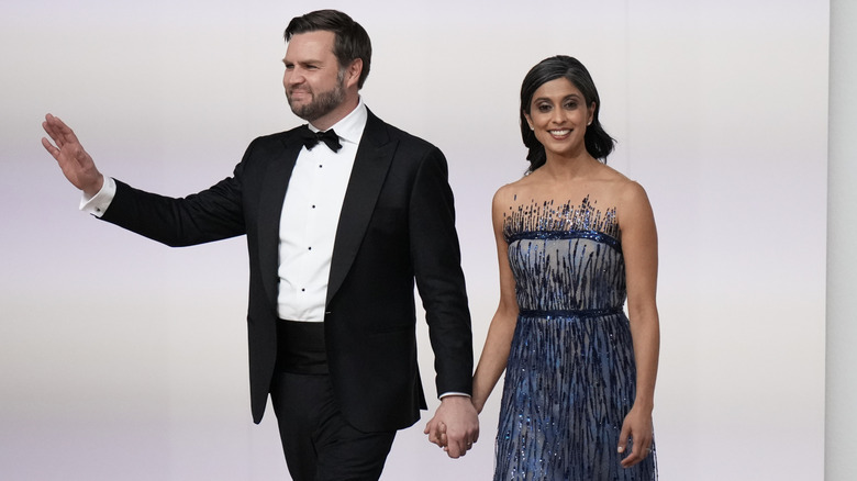 JD and Usha Vance strut across a stage, holding hands, in formal wear