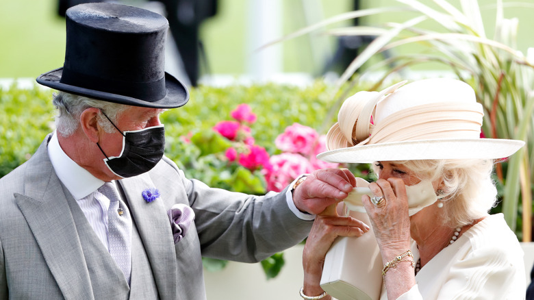 King Charles helping Queen Camilla with face mask 