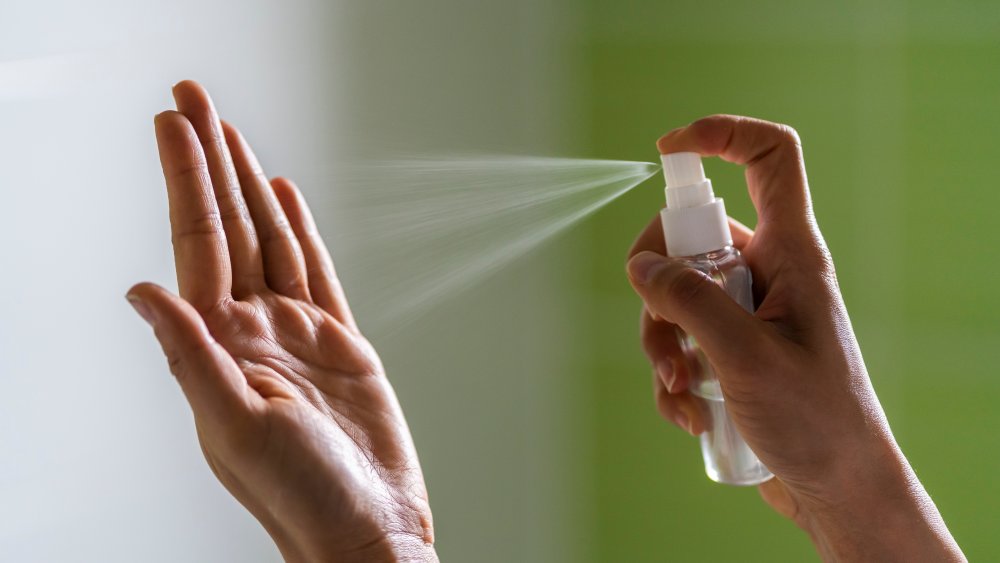 Woman spraying hands with alcohol