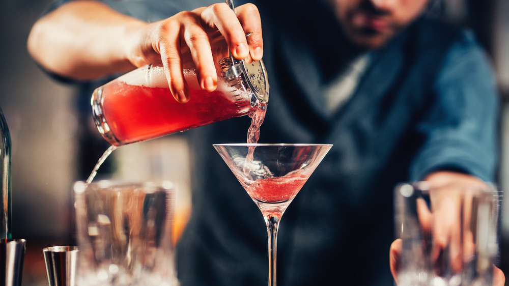 Bartender pouring a Cosmopolitan into martini glass