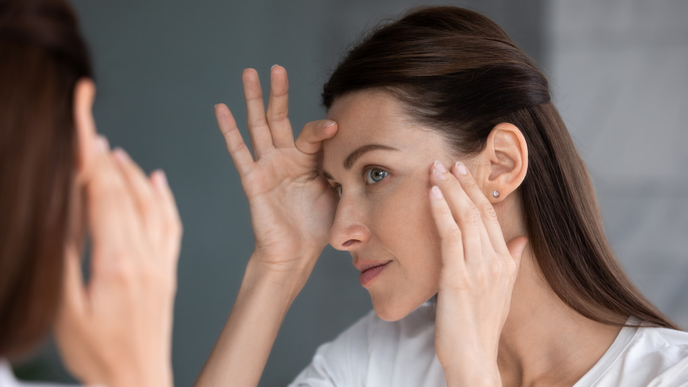 woman examining her face in the mirror