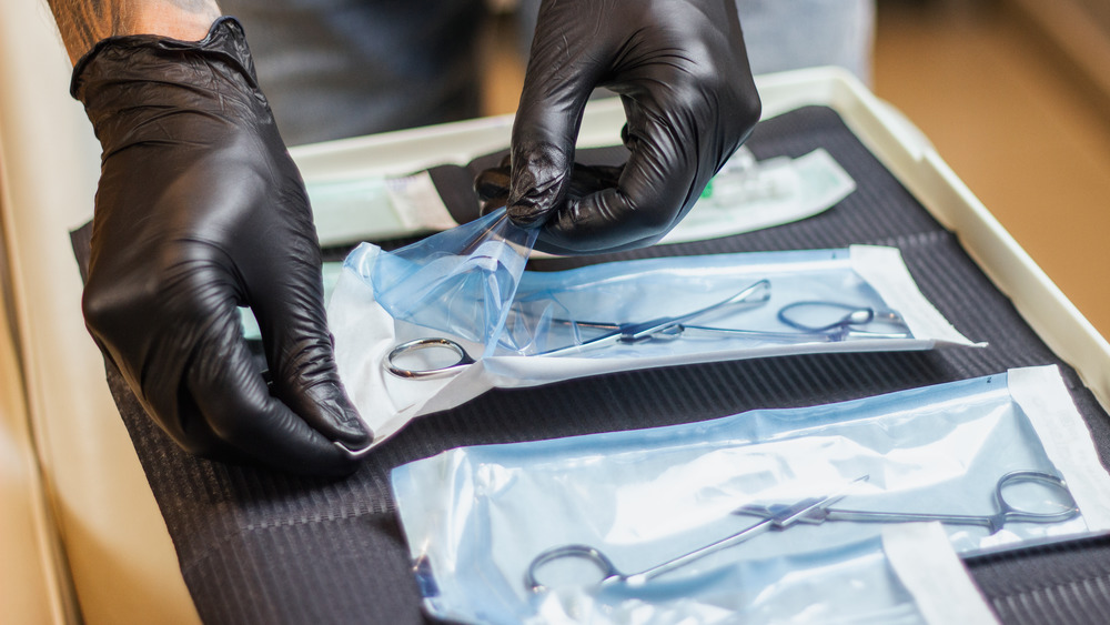 Gloved hands opening sterile equipment 