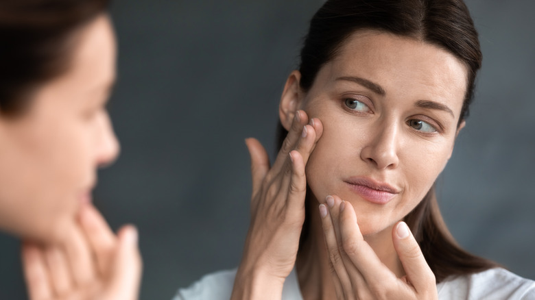 Woman looking at her skin in the mirror