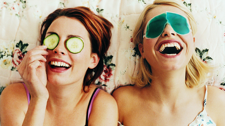 Women laughing with cucumbers on eyes 