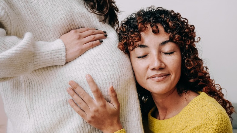 A woman holding a pregnant woman 