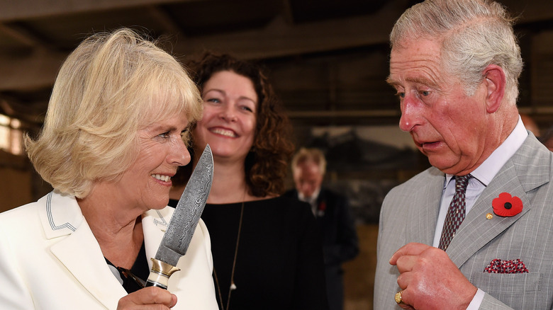 Queen Camilla holding knife to King Charles