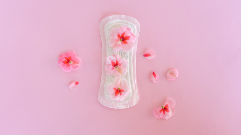 A menstrual pad with pink flowers on a pink background.