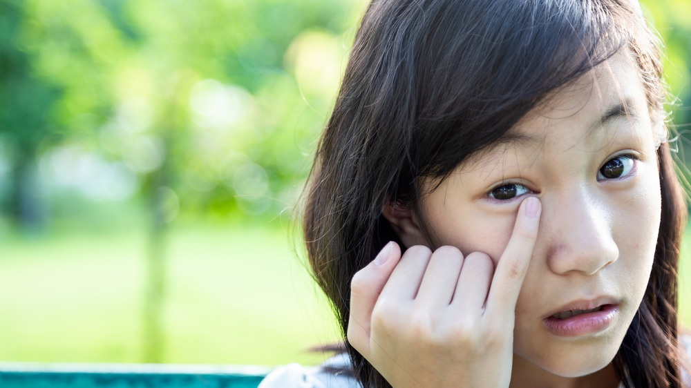 Woman touching itchy eye