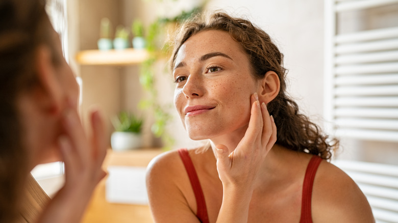 woman examining skin in mirror