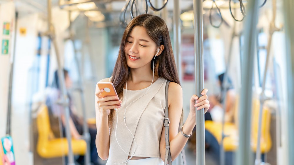 A woman riding the subway looking at her phone