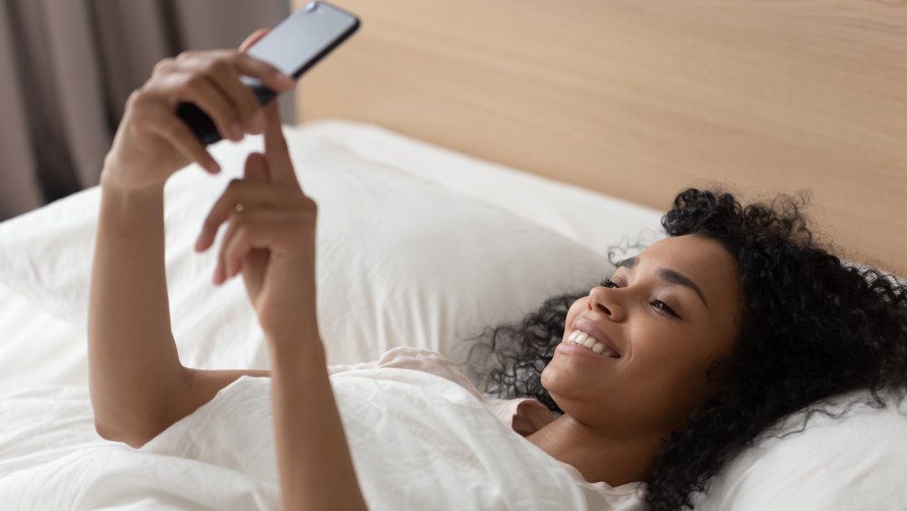 A woman in bed using a dating app