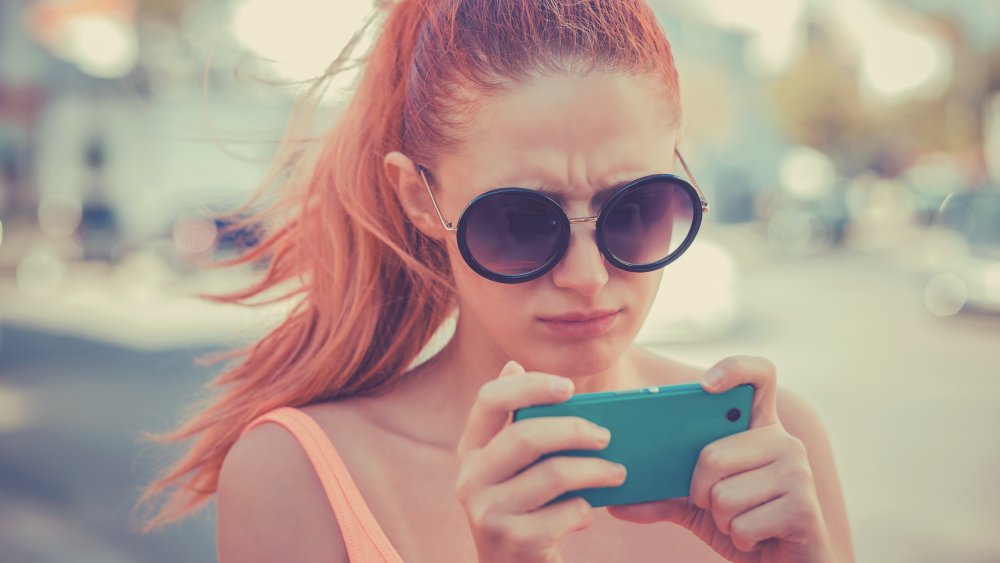 A woman looking at her phone, frustrated