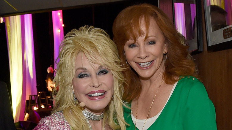 Smiling Dolly Parton and Reba McEntire posing for photo together