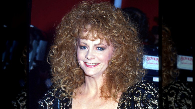 Reba McEntire on the red carpet with a sparkly dress and very big, very curly hair