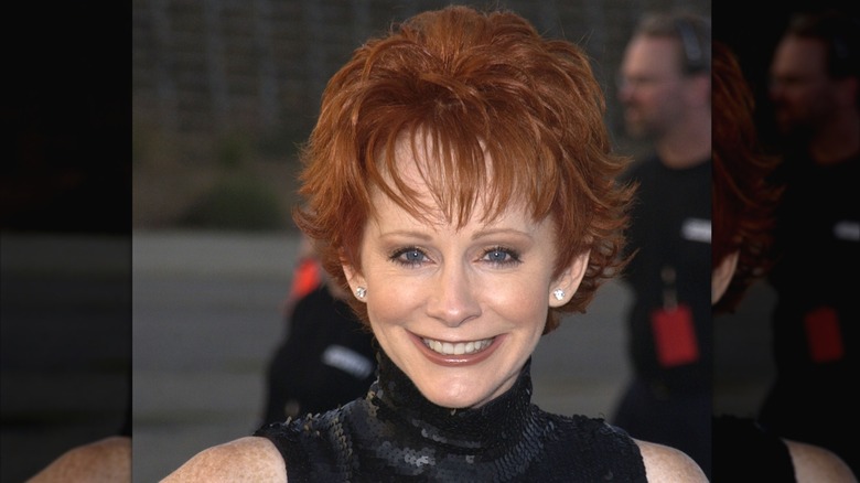 Reba McEntire outside smiling at camera with her hair cut above her ears and flipped out