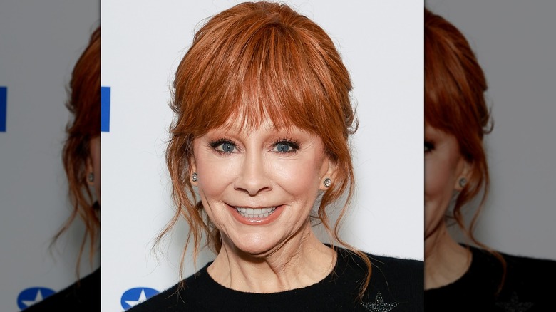 Reba McEntire with orange shadow, lipstick blush, awkward grin.