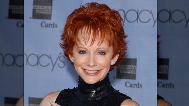 Reba McEntire with pixie haircut, thin brows, thin lips, big smile.