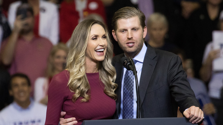 Eric and Lara Trump sharing a microphone behind a podium