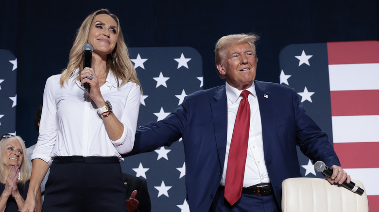 Donald Trump patting Lara Trump on the back while she holds a microphone