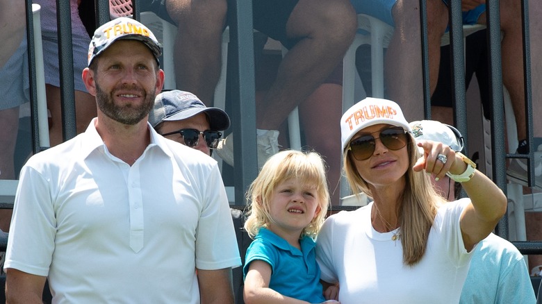 Lara and Eric Trump wearing caps with their daughter