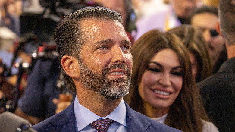 Kimberly Guilfoyle smiling behind Donald Trump Jr.