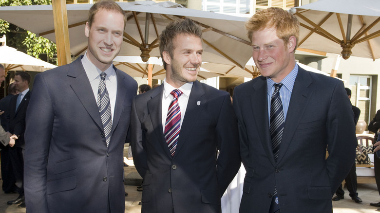 Prince Harry and Prince William smiling with David Beckham