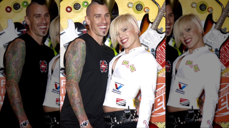 Pink with platinum hair and a white motorcycle jacket and Carey Hart in black muscle shirt with a mohawk