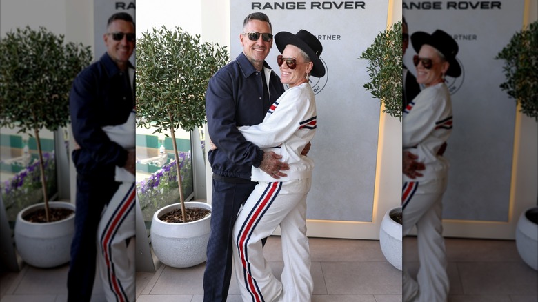 Pink in a white track suit with sunglasses and hat with Carey Hart in black with sunglasses