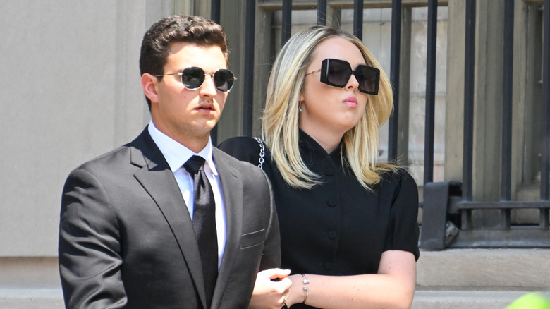 Michael Boulos and Tiffany Trump walking arm in arm wearing sunglasses