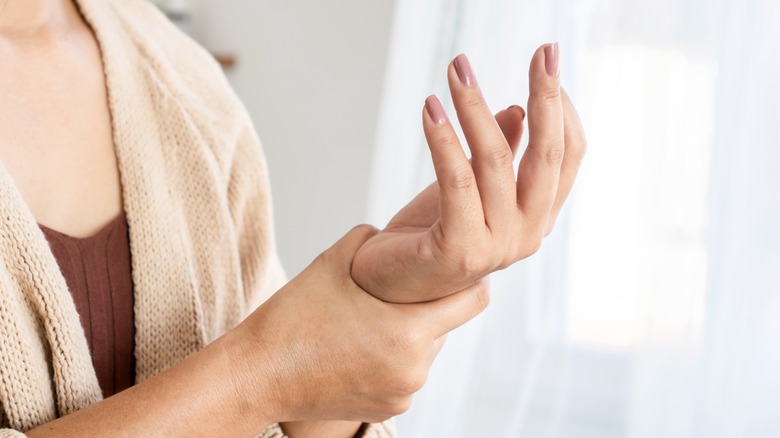 Woman holding hand, showing discomfort