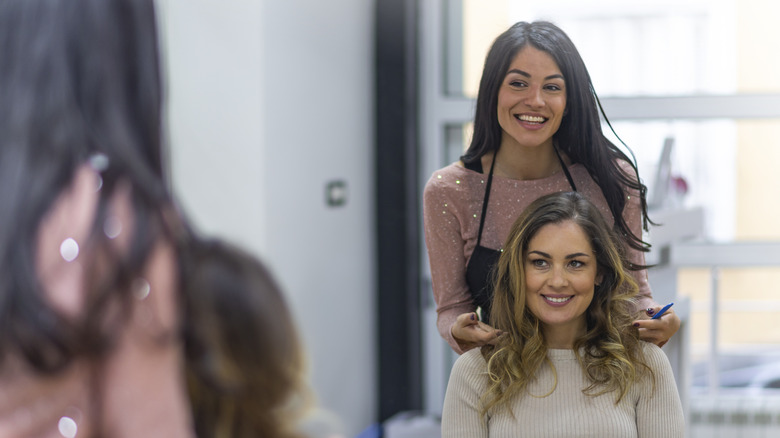 Hairstylist smiling at client in mirror