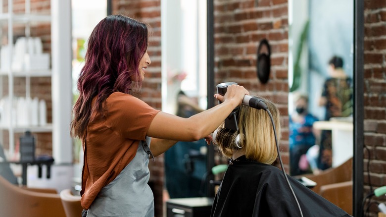 Hairdresser smiling while doing client