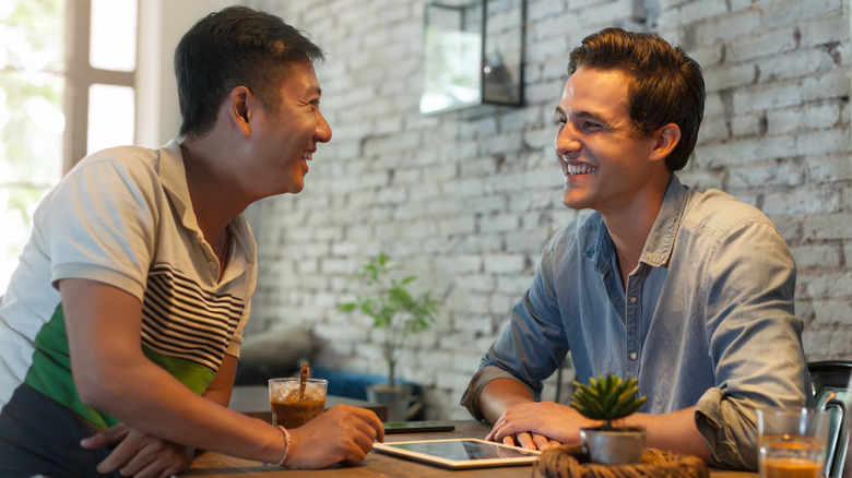 Two men smiling across from each other at a table