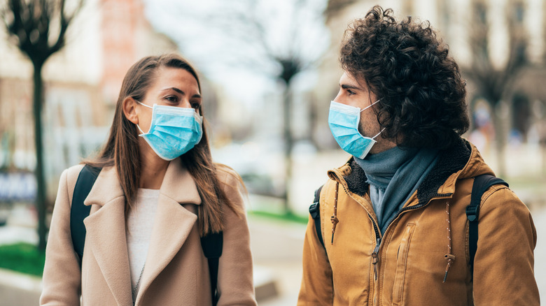 Two people wearing coats and masks