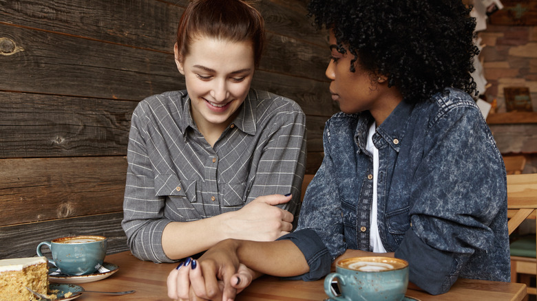 Lesbian couple holding hands over coffee