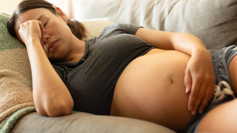 uncomfortable pregnant woman laying on a couch