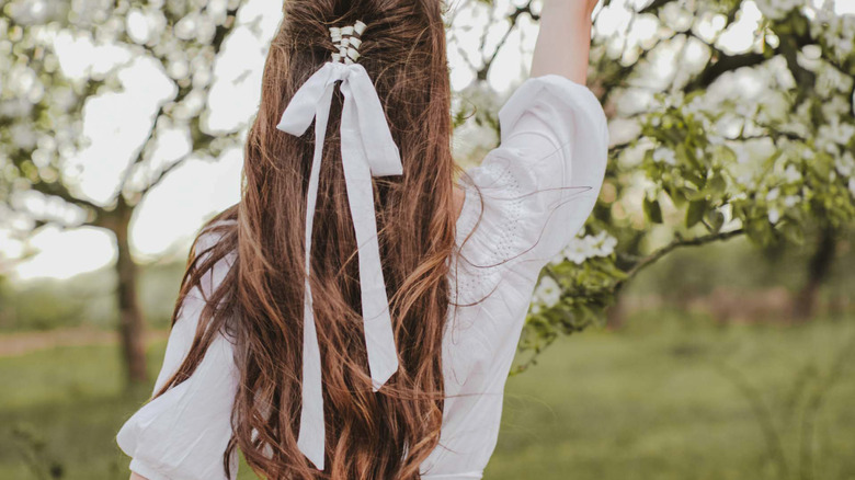 A girl with long dark hair and a white ribbon braided in