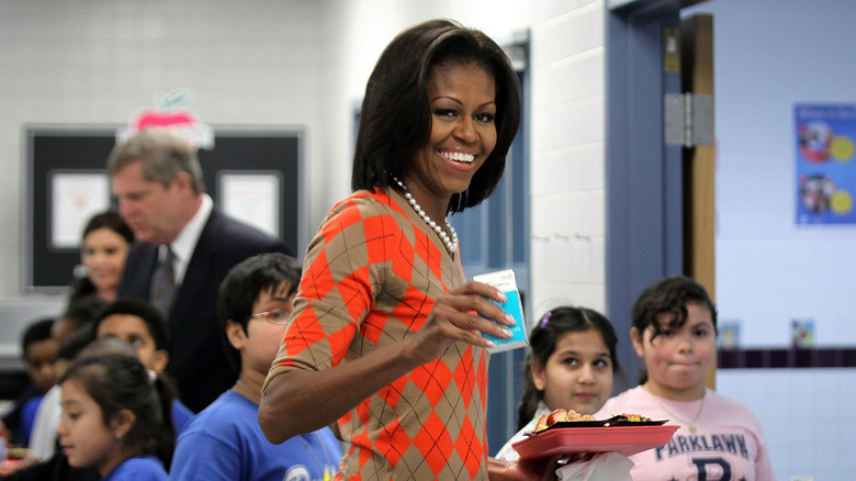 Michelle Obama holding a lunch tray and a carton of milk at a school event