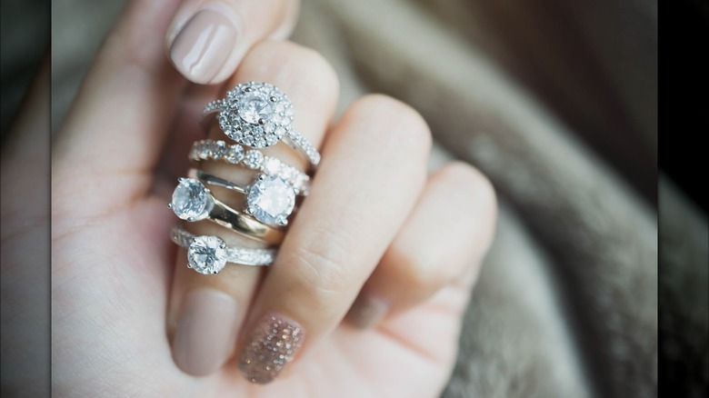 Hand with multiple engagement rings on middle finger 