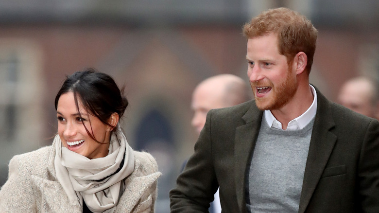 Meghan Markle and Prince Harry smiling and walking