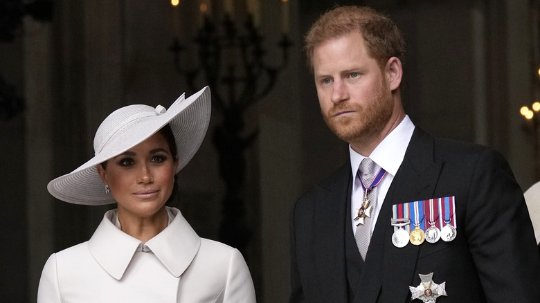 Prince Harry looks grumpy alongside Meghan Markle