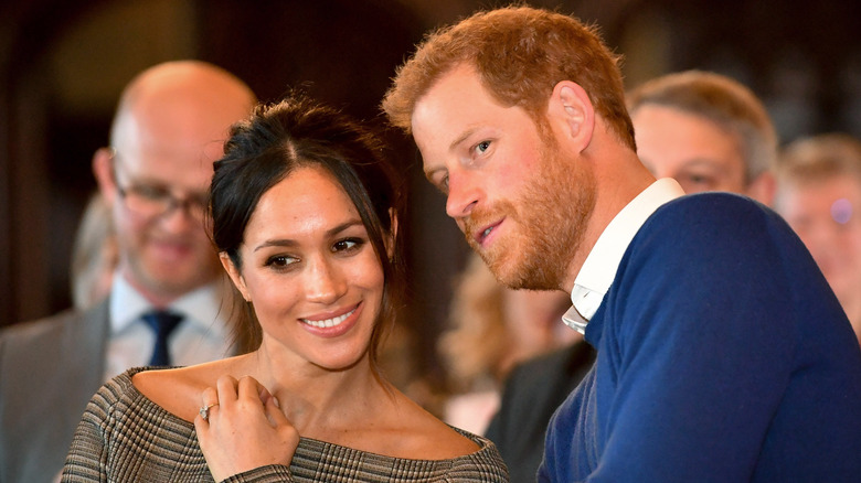 Meghan Markle and Prince Harry smiling and leaning towards one another