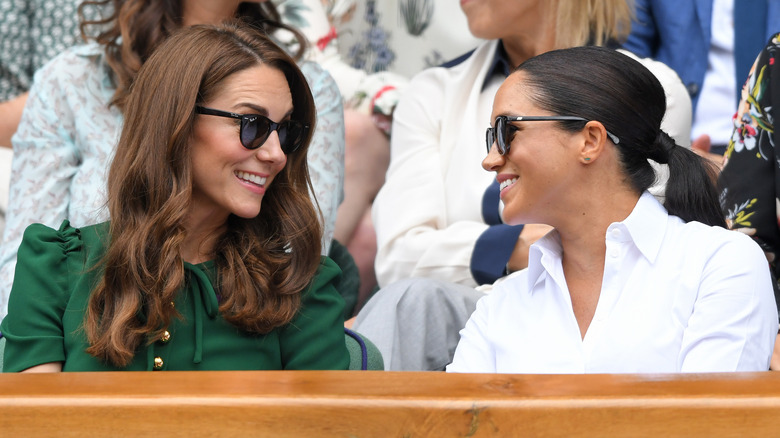 Kate Middleton and Meghan Markle smile at each other.