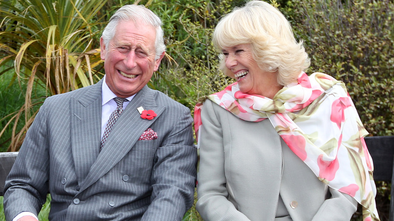 Prince Charles and Camilla Parker Bowles laughing on bench