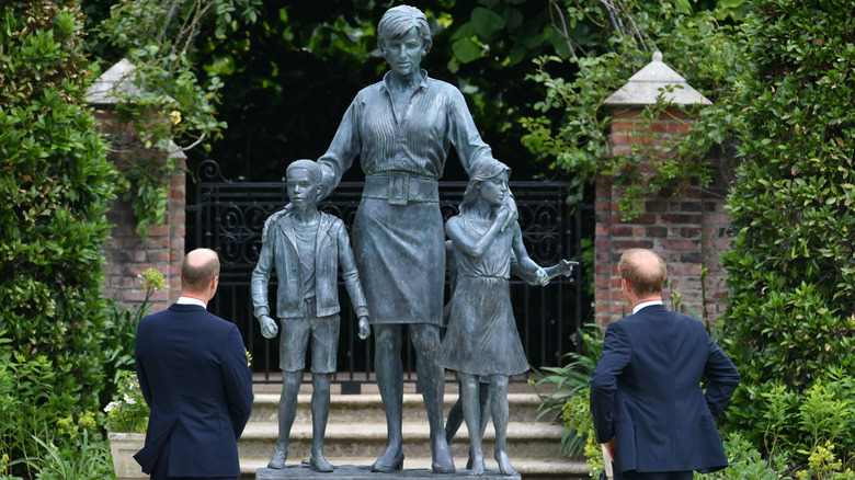 Princes William and Harry look at Princess Diana's statue