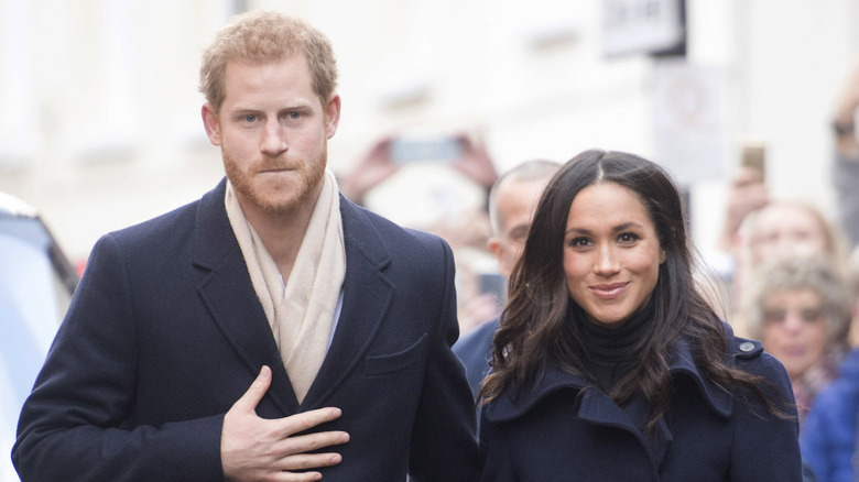 Meghan and Harry walking in black coats