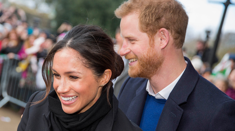  Meghan and Harry smiling together looking away from camera