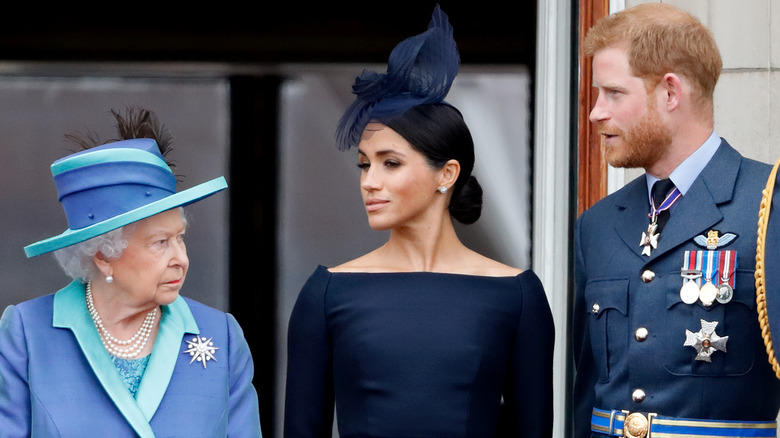 Queen Elizabeth, Meghan Markle, and Prince Harry standing together