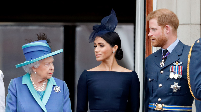 Queen Elizabeth II, Meghan Markle, and Prince Harry posing 