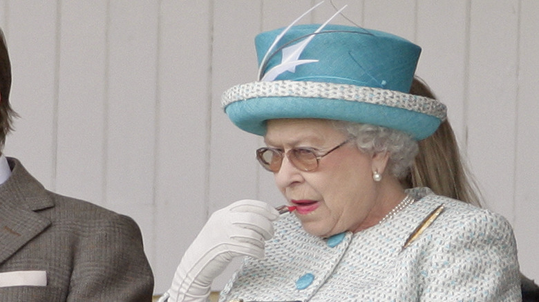 Queen Elizabeth applying lipstick